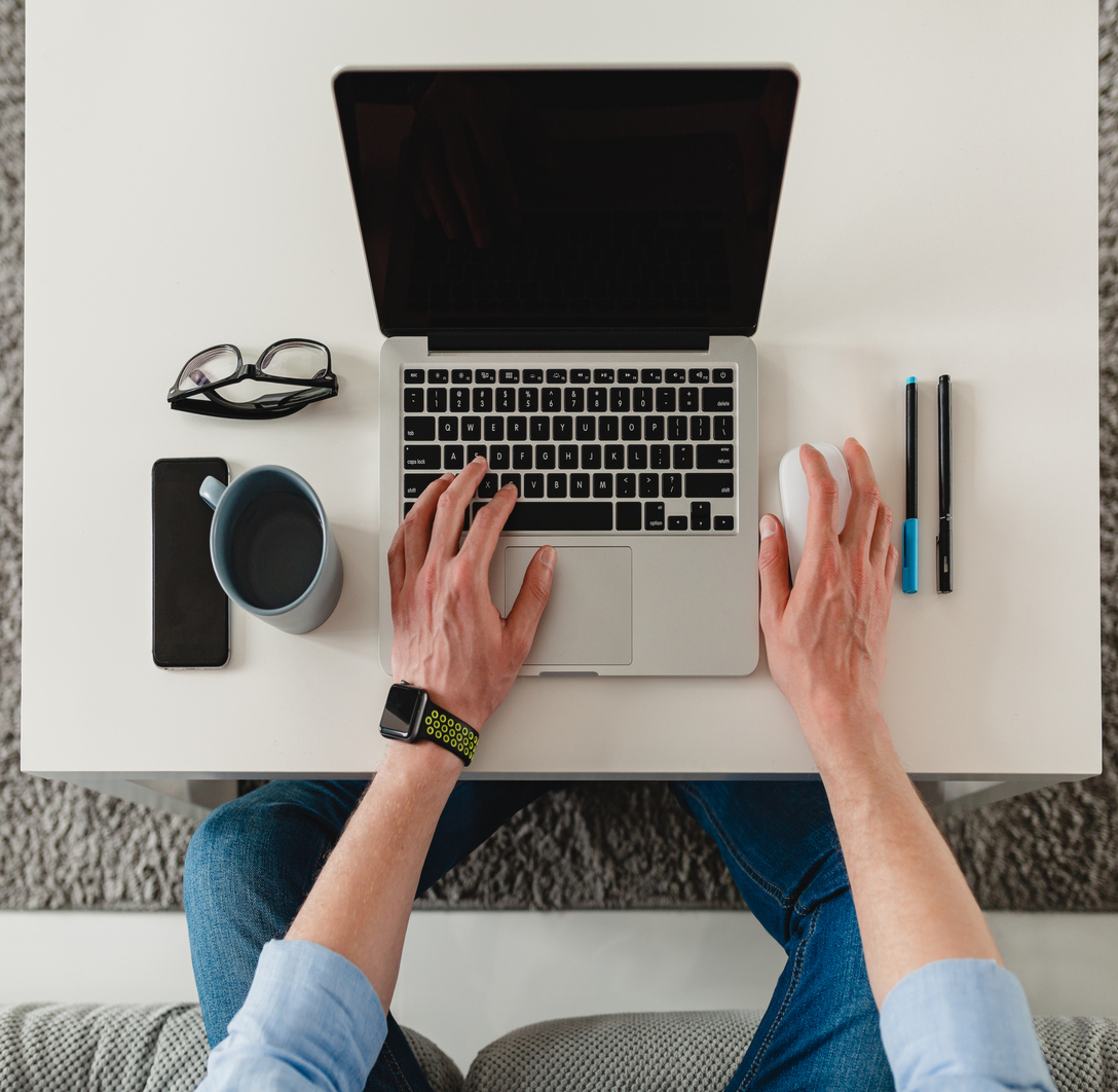 flat lay view from above on table workplace close-up man hands at home working typing on laptop online freelancer job, black empty screen, stationery